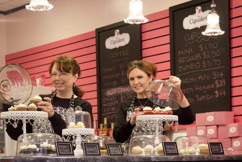 Cupcakerie employees setting up cupcake displays