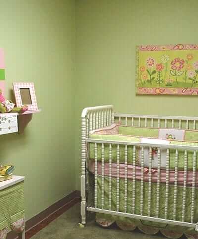 Nursery/ baby bedroom with green walls, furniture, and toys