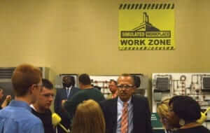people standing around in area labeled "Simulated Workplace Work Zone" wearing safety goggles