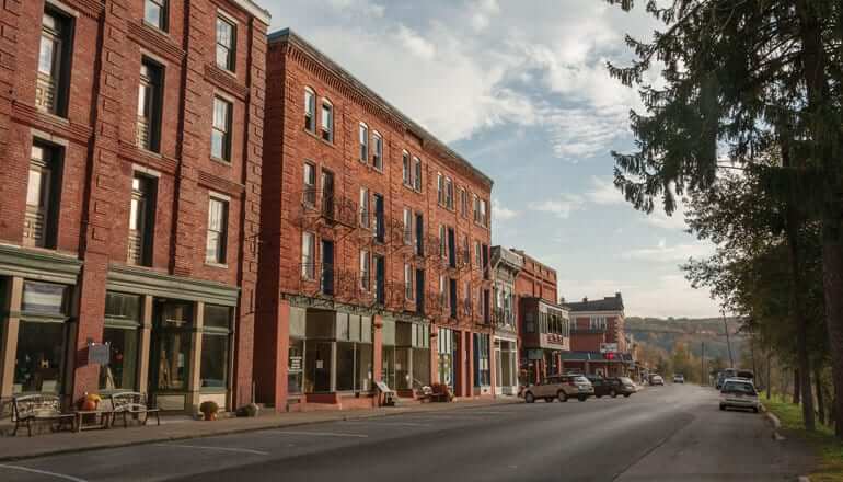 Brick buildings with stores on the bottom level and parking spots lines up in front of them